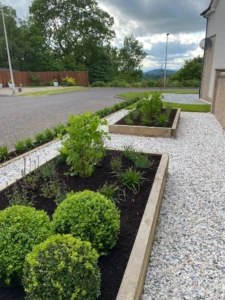 "Creating a Garden Oasis: Our skilled team carefully installs a raised sleeper bed, bringing beauty and functionality to this stunning garden transformation in Stirling. The raised bed offers a designated area for gardening, providing easy access and improved drainage for plants. With precision and expertise, we ensure a sturdy and attractive addition to the landscape, allowing homeowners to effortlessly cultivate their own oasis of natural beauty." "An image showing the installation process of a raised sleeper bed in a garden. The workers are carefully positioning and securing the wooden sleepers to create the structure of the bed. The bed is being filled with rich, fertile soil, ready for planting. The raised bed will provide a designated area for gardening, offering easy access and improved drainage for plants. The installation is being carried out with precision and expertise, ensuring a sturdy and attractive addition to the garden landscape."